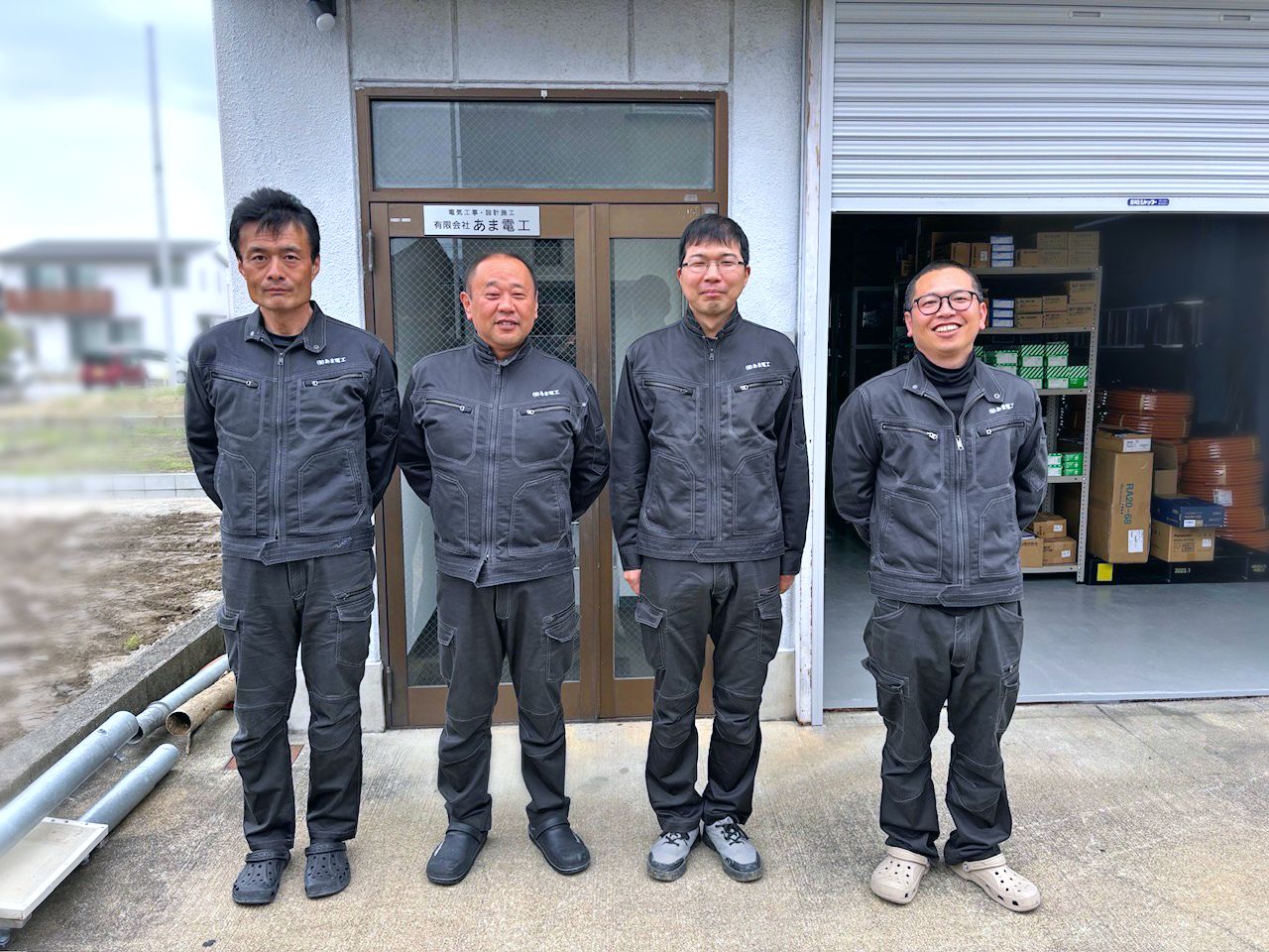 あま電工の社員4名が事務所兼倉庫の前に並んだ集合写真